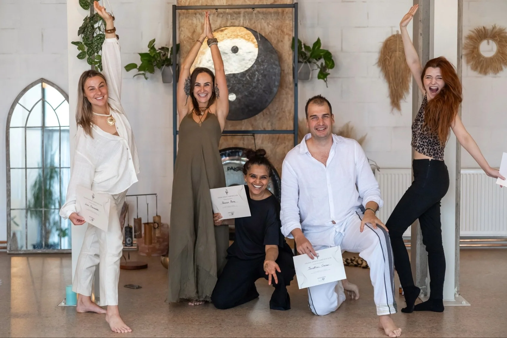 a group of people are happy and smiling, holding certificates after finishing kundalini activation facilitator training in luv yourself space with teacher standing next to them