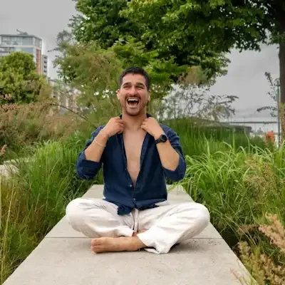 A man sitting outside on the ground and smiling