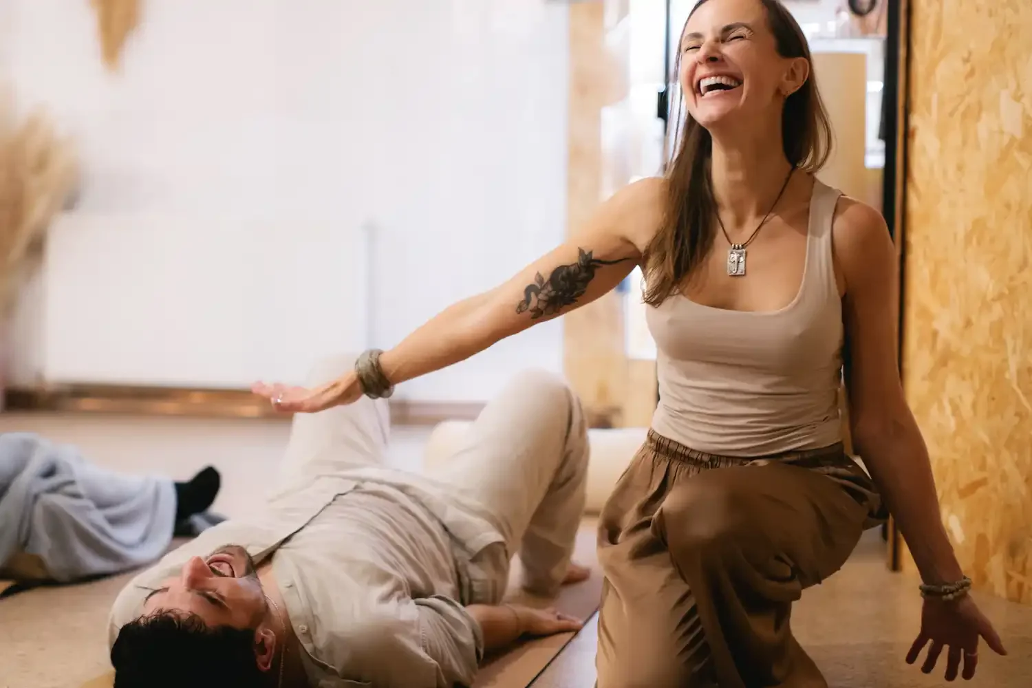A man smiling and happy is lying on the floor and a smiling happy woman is holding her hand above him looks like sending energy to him.