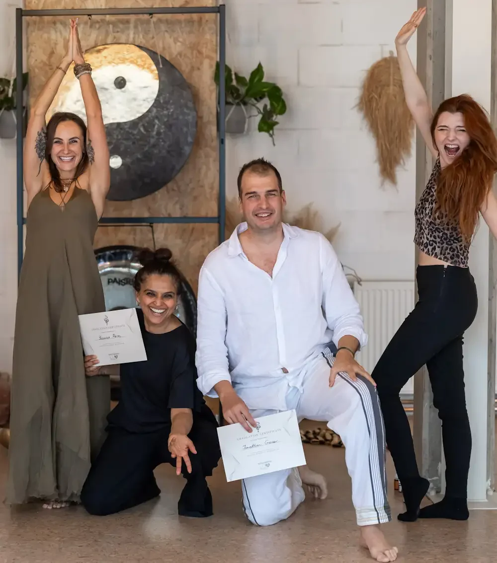 a group of people are happy and smiling, holding certificates after finishing kundalini activation facilitator training in luv yourself space with teacher standing next to them