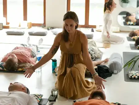 A woman is facilitating an energy session with people calmly on the floor and energy is being present