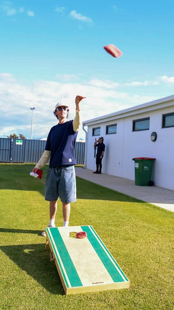 A young man in casual clothes playing bean bag toss at Bunbury Turf Club Family Fun Day.