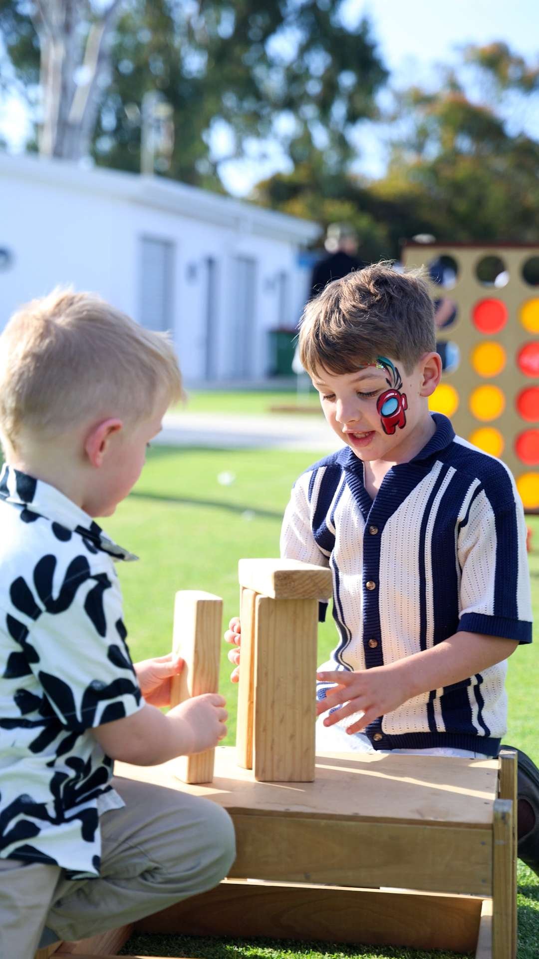 Two young boys playing Connect Four outdoors on a sunny day at Bunbury Turf Club Family Fun Day.