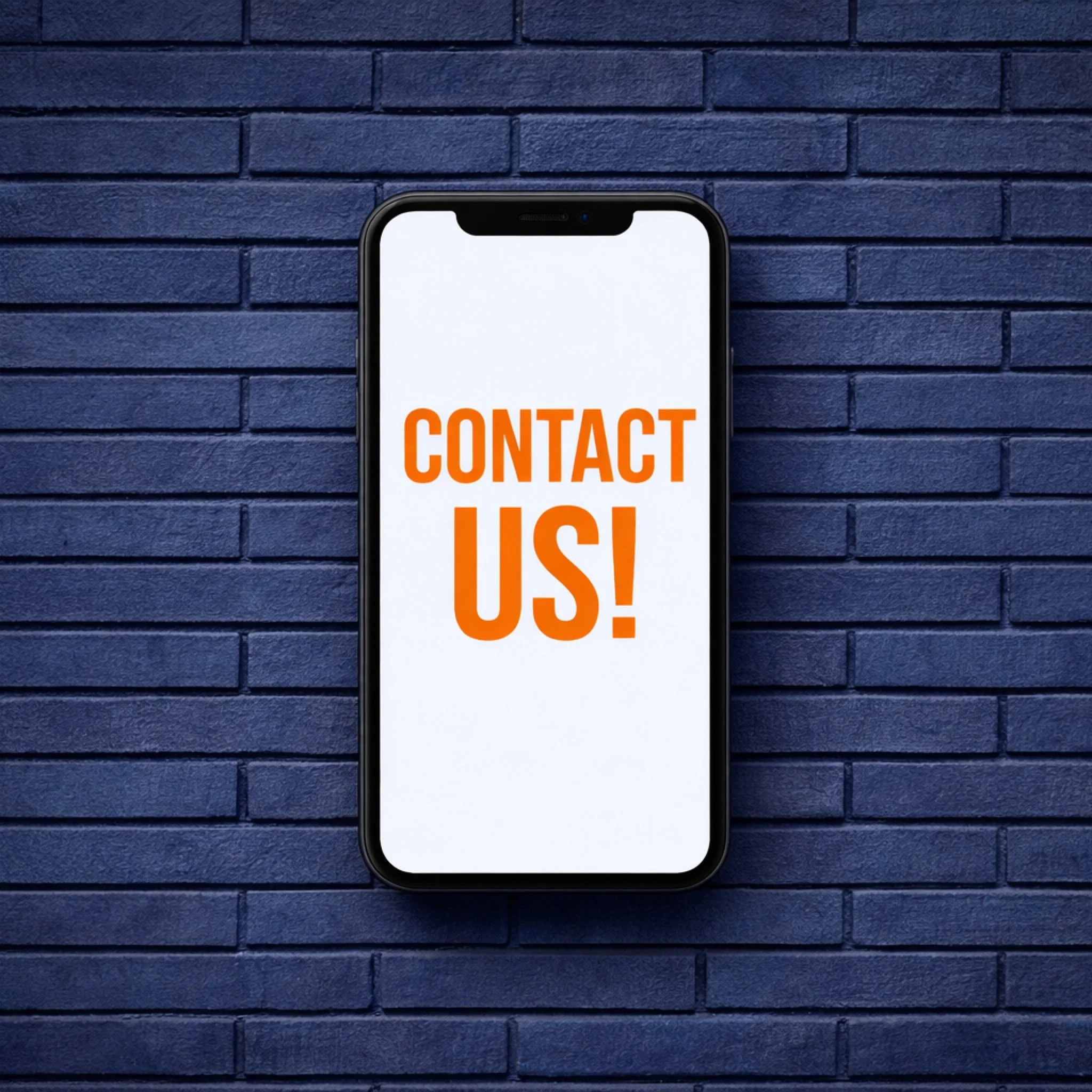 Smartphone with a screen displaying 'CONTACT US!' in bold orange letters, mounted against a dark blue brick wall.
