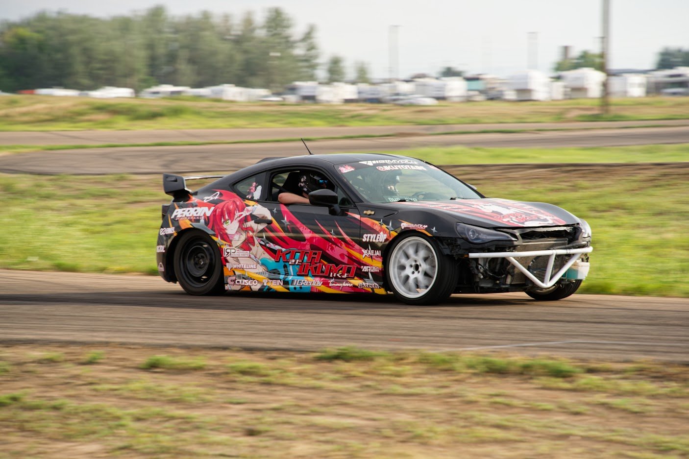 Car with colorful anime-style graphics racing on a track.