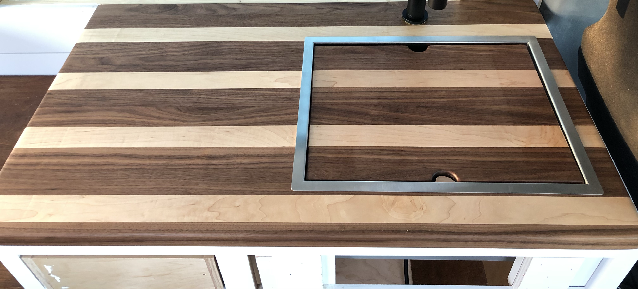 Wooden kitchen island with an inset metal frame for a cooktop or sink opening.