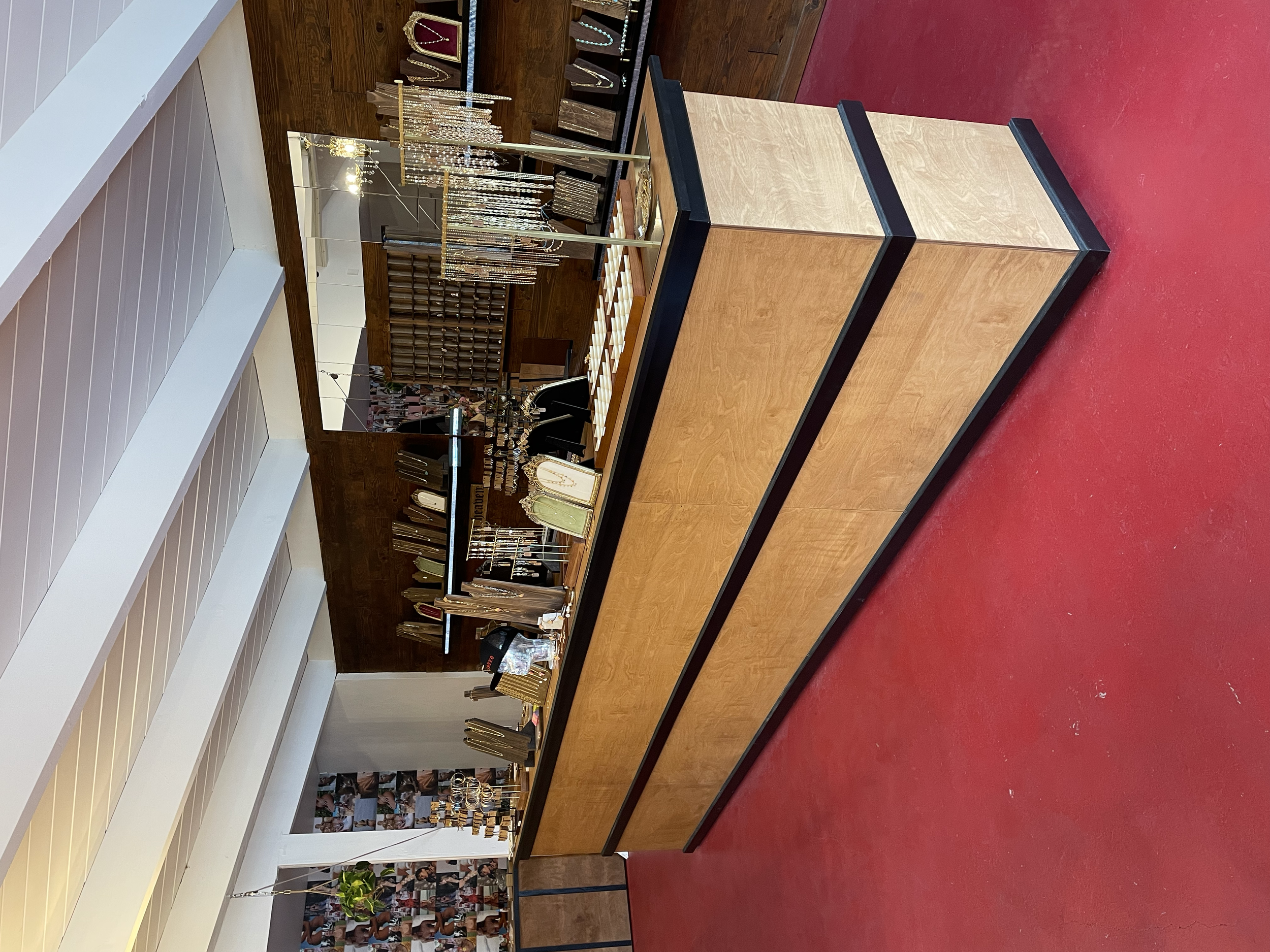 Empty retail jewelry display counter with a mirror and jewelry racks in the background.