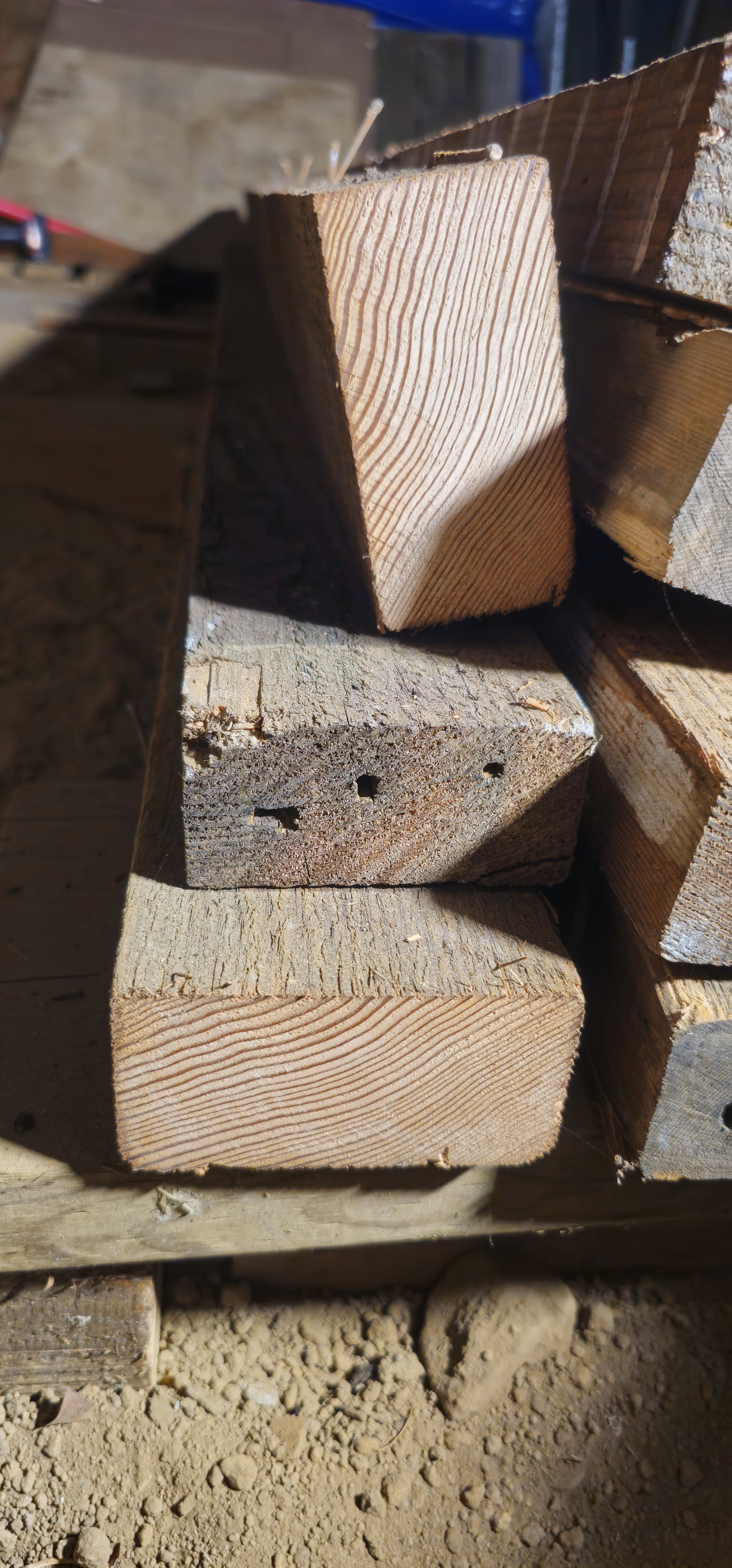 Close-up of stacked reclaimed old growth lumber pieces showing cross-section and wood grain.