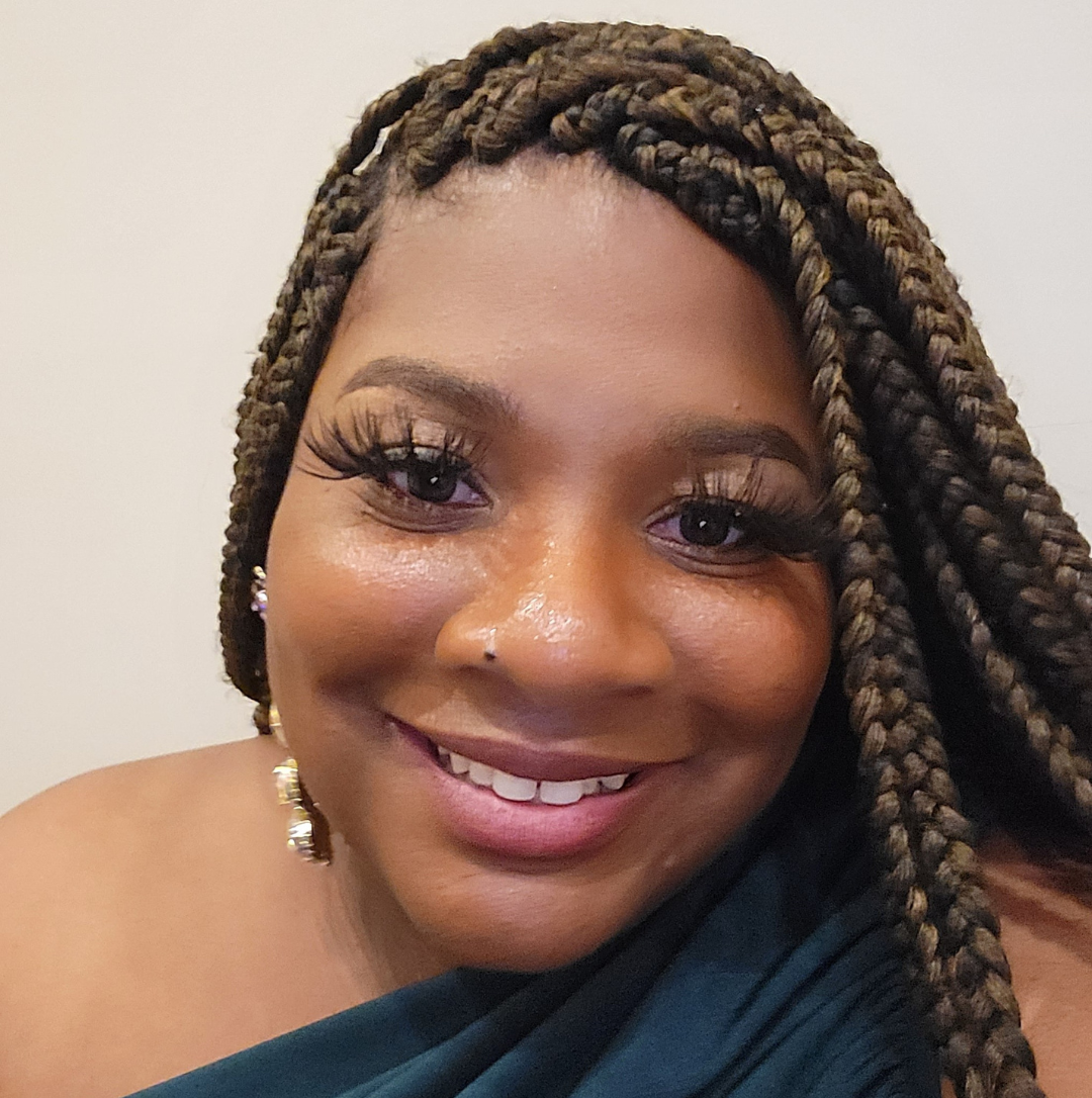 A woman with braided hair smiling at the camera.