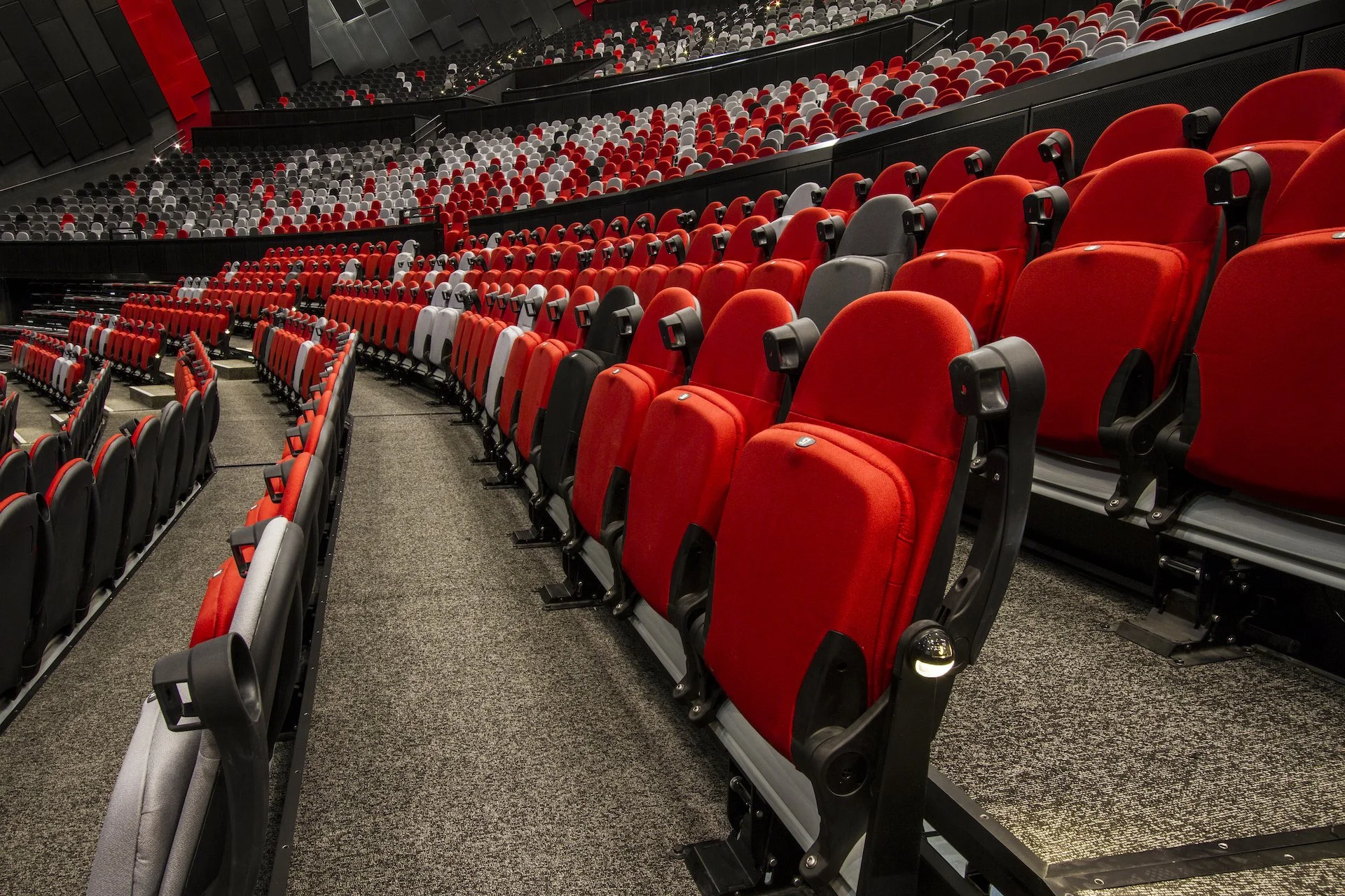 Empty auditorium with red and black seats arranged in curved rows.
