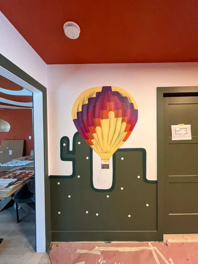 Interior wall with a painted design of a hot air balloon above a cactus, with a desert scene at the bottom.