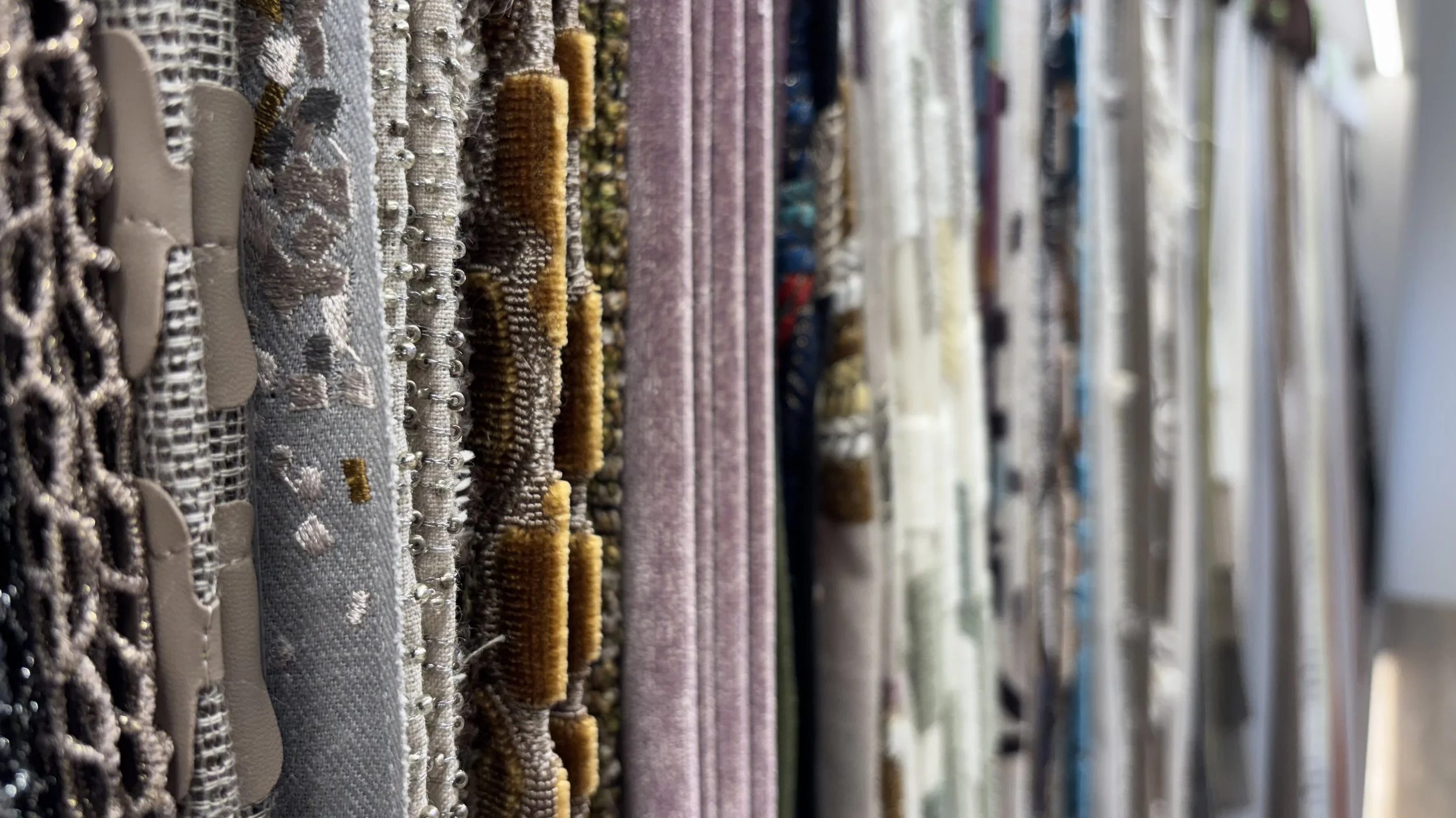 Filato e tessuti di vari colori e texture appesi in un negozio.