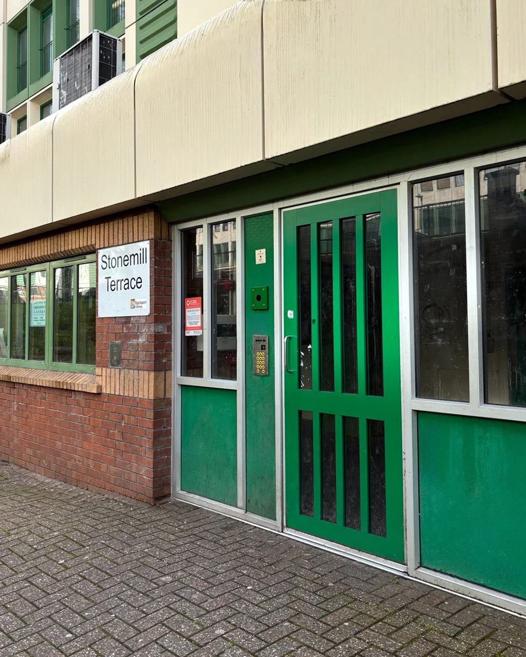 Exterior of a building with a green door, windows, and a white sign reading 'Stonemill Terrace'.
