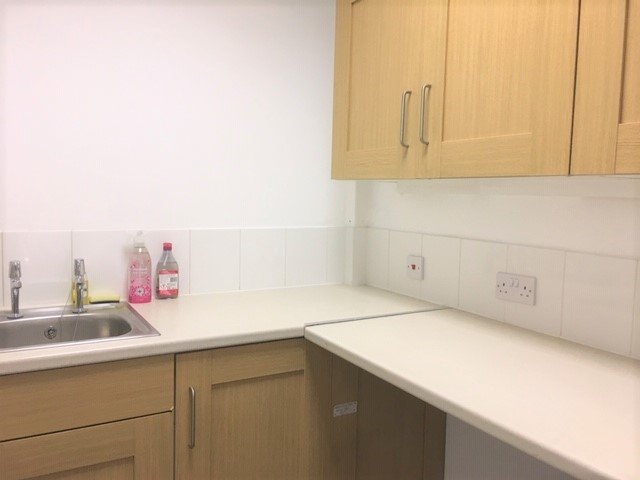 Kitchen countertop with pink soap, hand sanitizer, and a sink with a faucet.