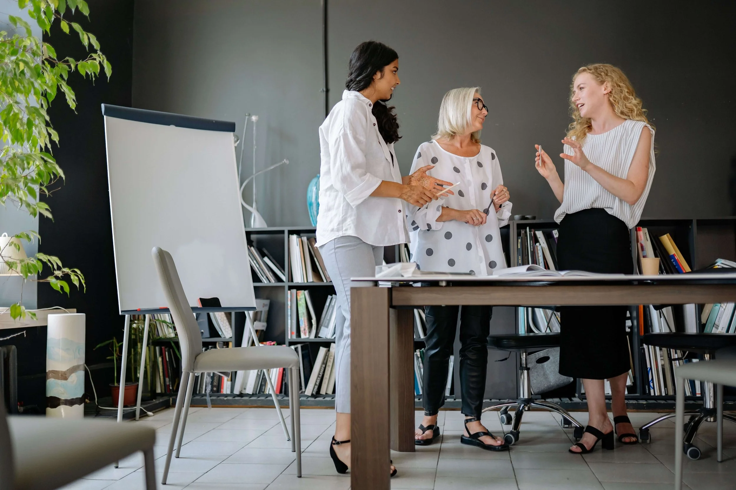 three women in an office having a conversation