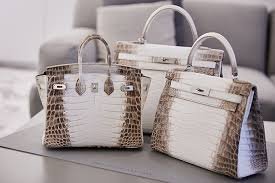 Three handbags with a crocodile pattern placed on a table