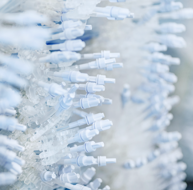 Close-up of multiple plastic medical nozzles or tubing connectors arranged in rows.