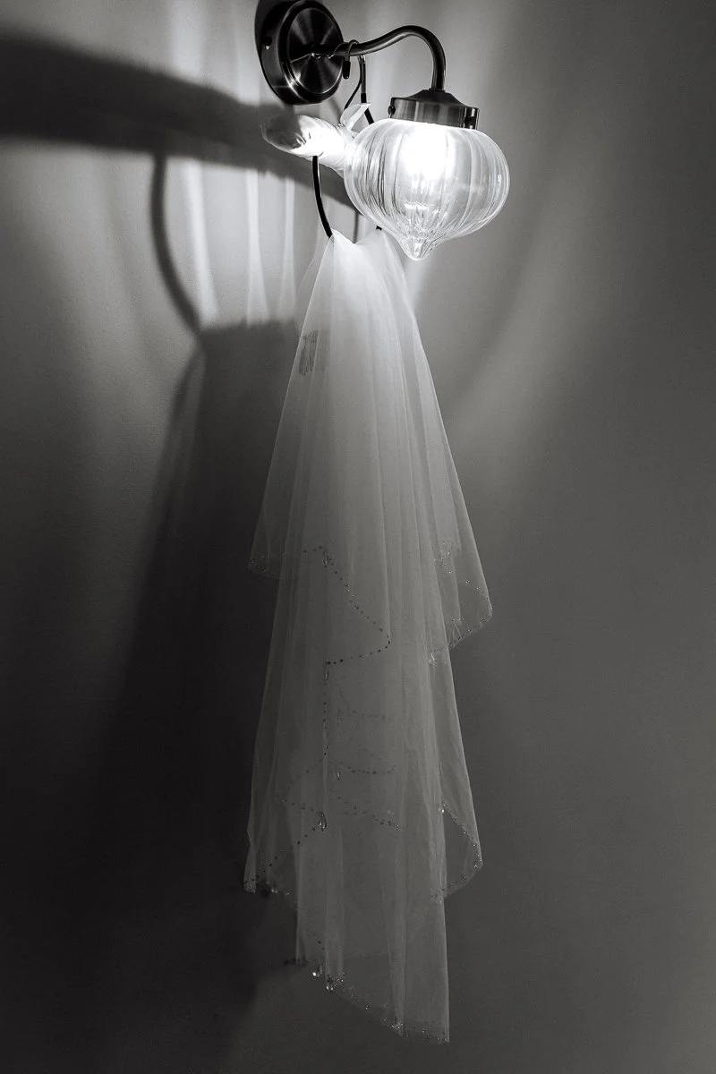  A black and white photo of a short veil hanging from a light fixture 