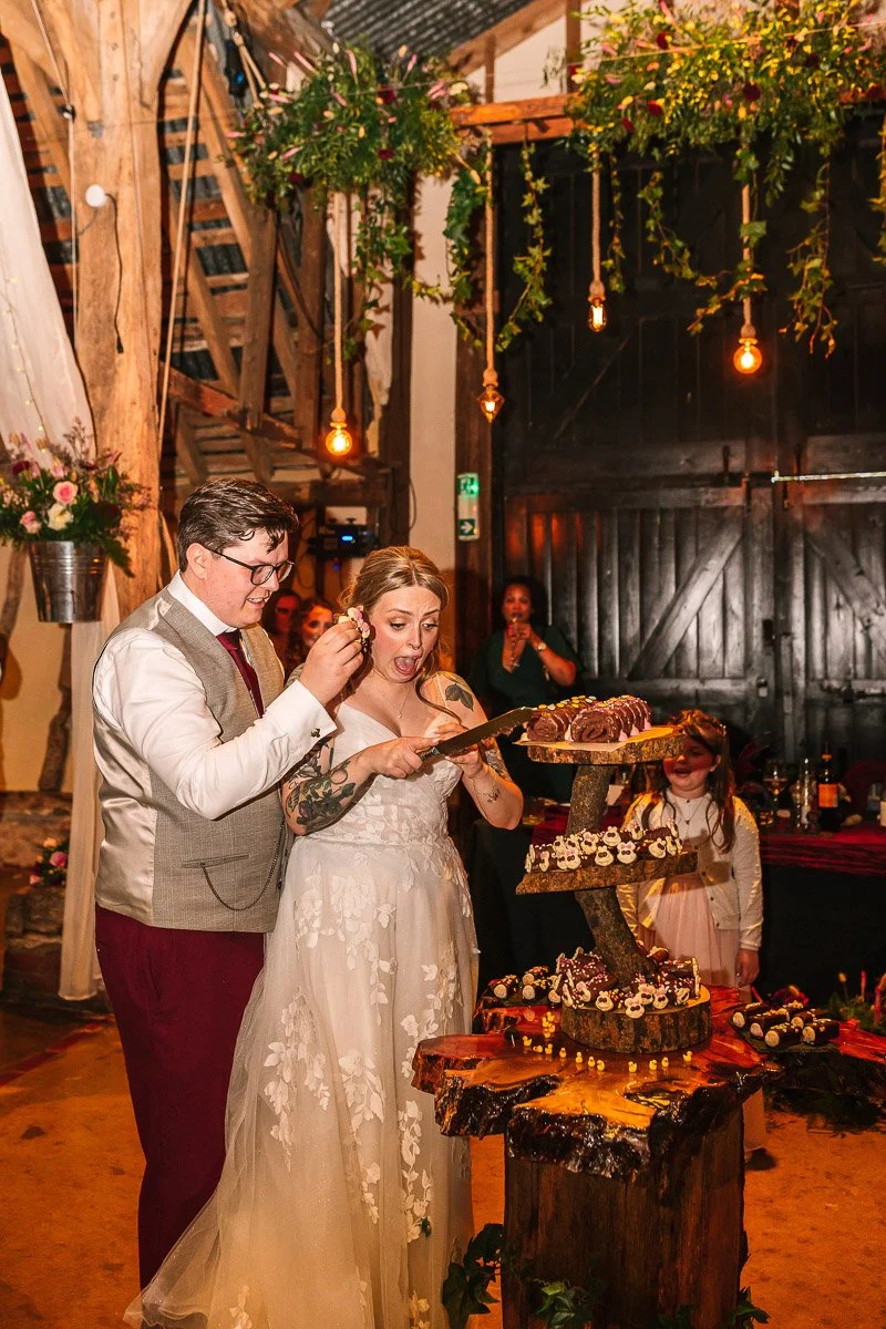  a bride and groom cut their Colin caterpillar cake while the bride looks shocked.  