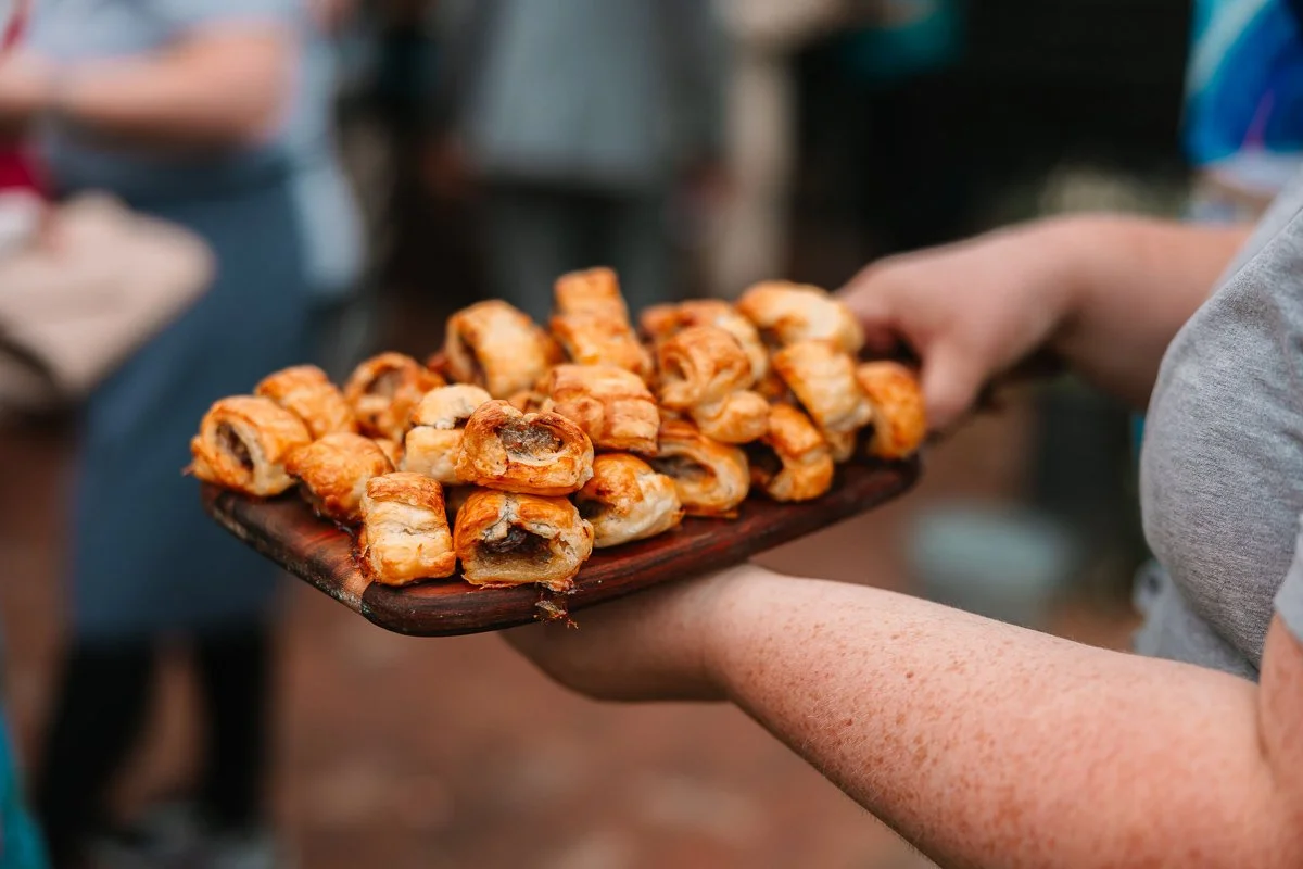  A wooden tray of sausage roll canapés 