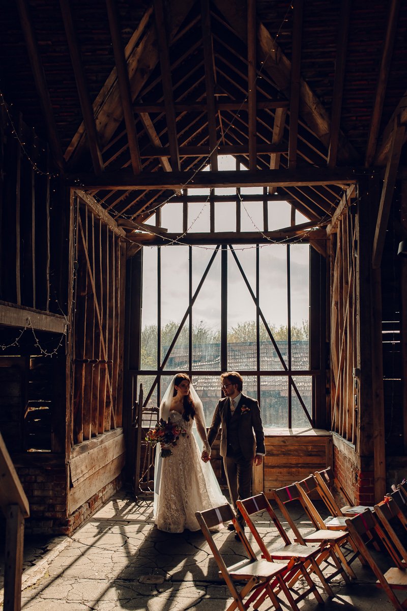  A couple wak in front of a big window in a rustic barn at Lodge farm barn    