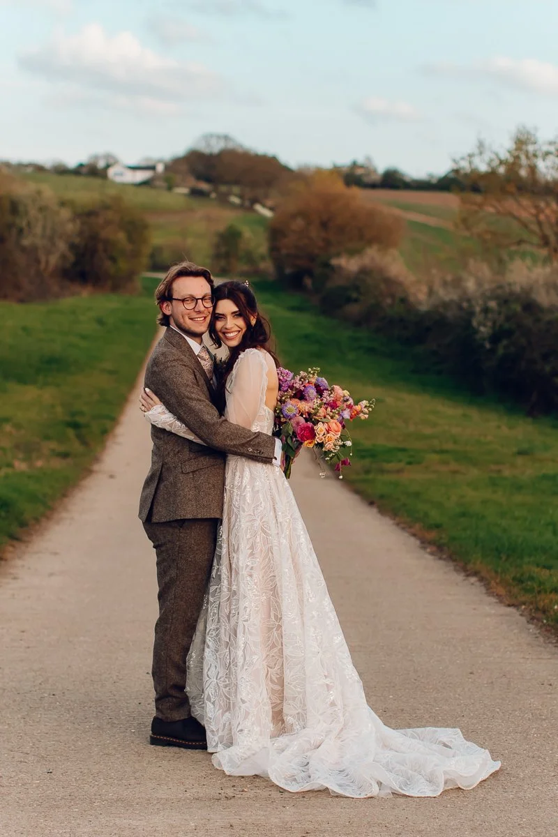  A bride and groom cuddle in the driveway of Lodge Farm Barns 