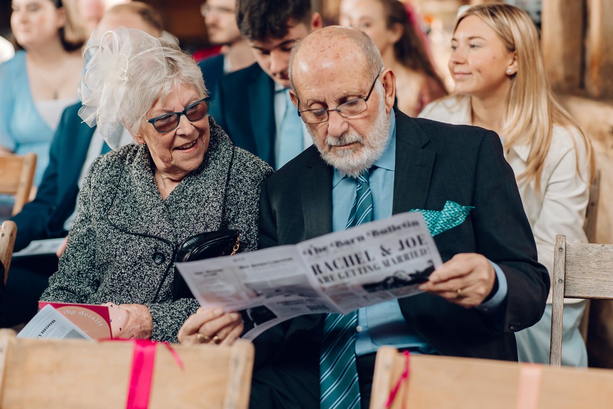  A couple sit together before the ceremony reading a wedding newspaper  