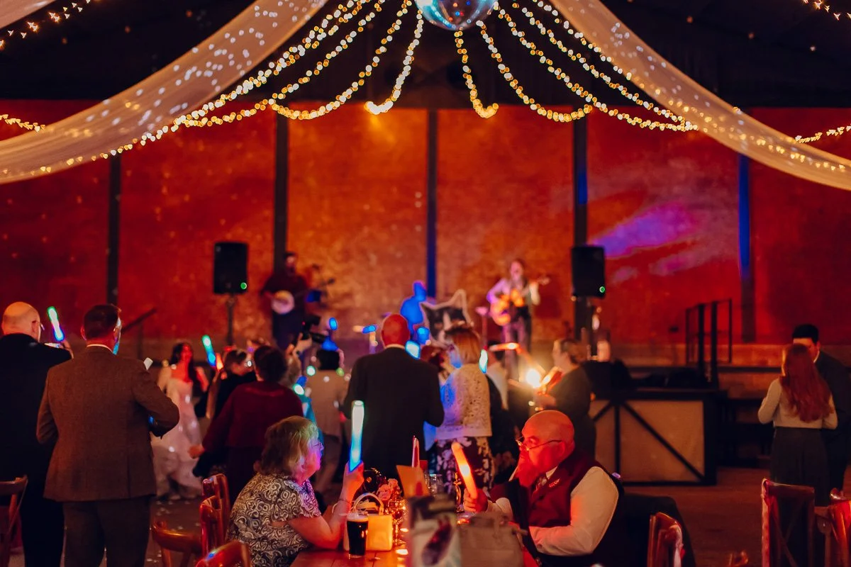  A photo of people on the dance floor with the band on the stage, above them is a curtain of fairy lights 