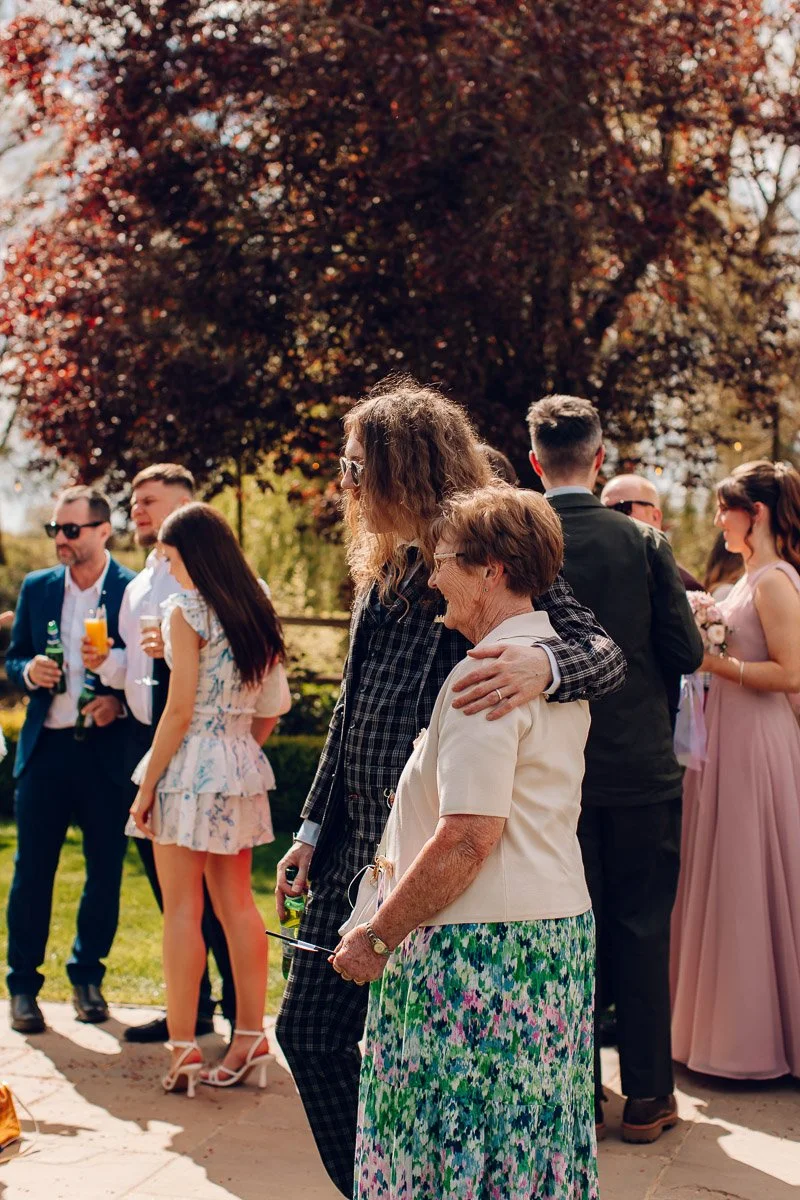 Documentary wedding photography capturing the groom sharing a hug with a family member at Houchins