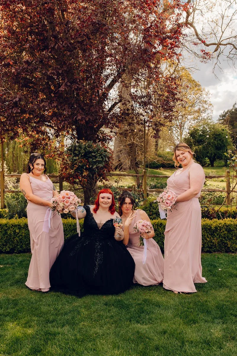 A Fun group photo of a bride in a black dress and bridesmaids at Houchins Wedding Venue