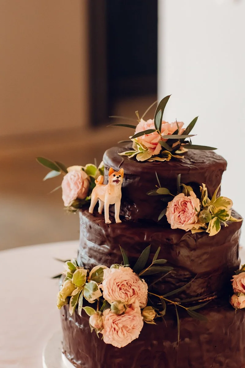 A close up of a dog figurine on a chocolate wedding cake