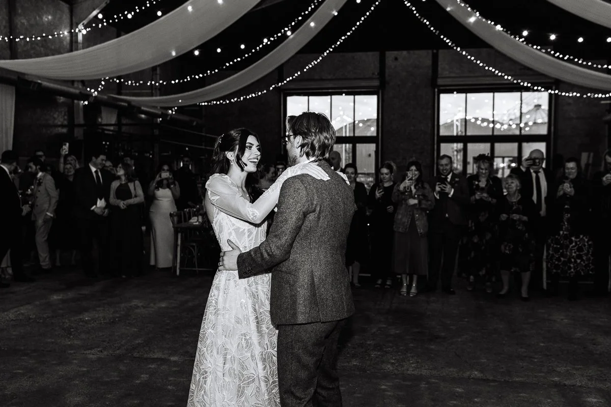 a black and white image of the bride smiling at the groom during the first dance