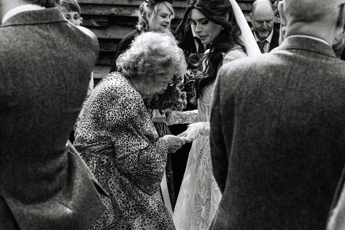 A black and white candid photo of a nan looking at the brides ring