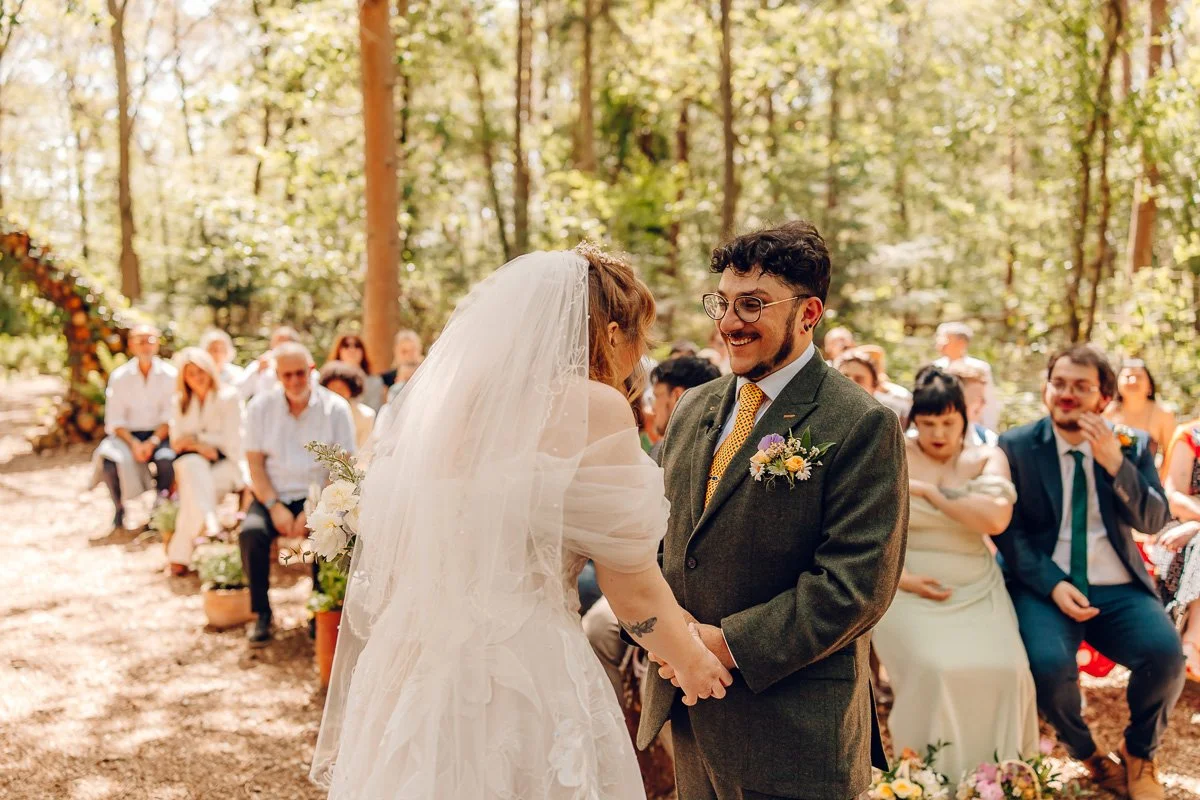 A groom laughs at his bride during their woodland ceremony at captains wood barn