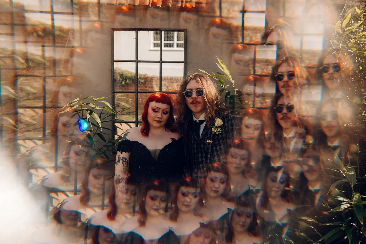 A kaleidoscope like image of the bride in a black dress and groom in a checked suit standing in some bamboo at houchins