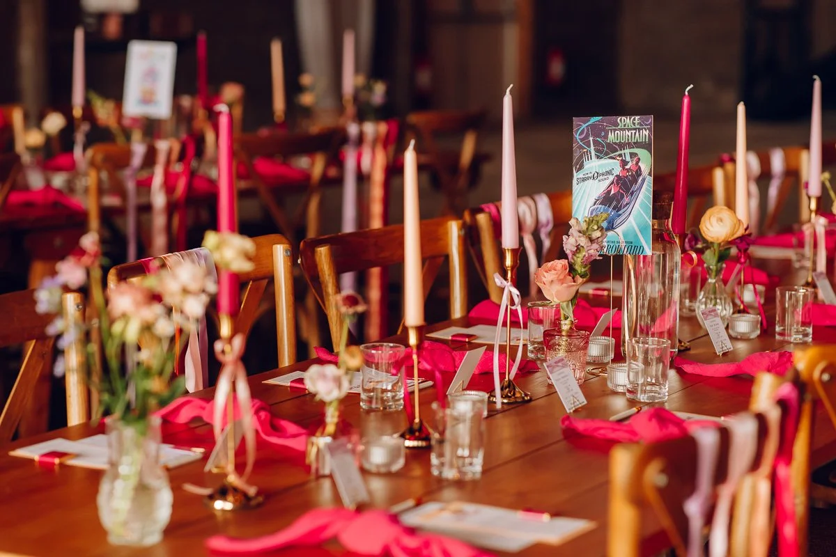 Bright pink and pastel pink wedding table scape with candles and a Disney space mountain table name