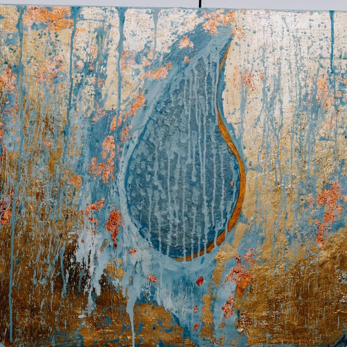 Abstract painting featuring a large blue shape with a gold outline, set against a background of textured gold, blue, and pinkish-orange splashes and streaks.