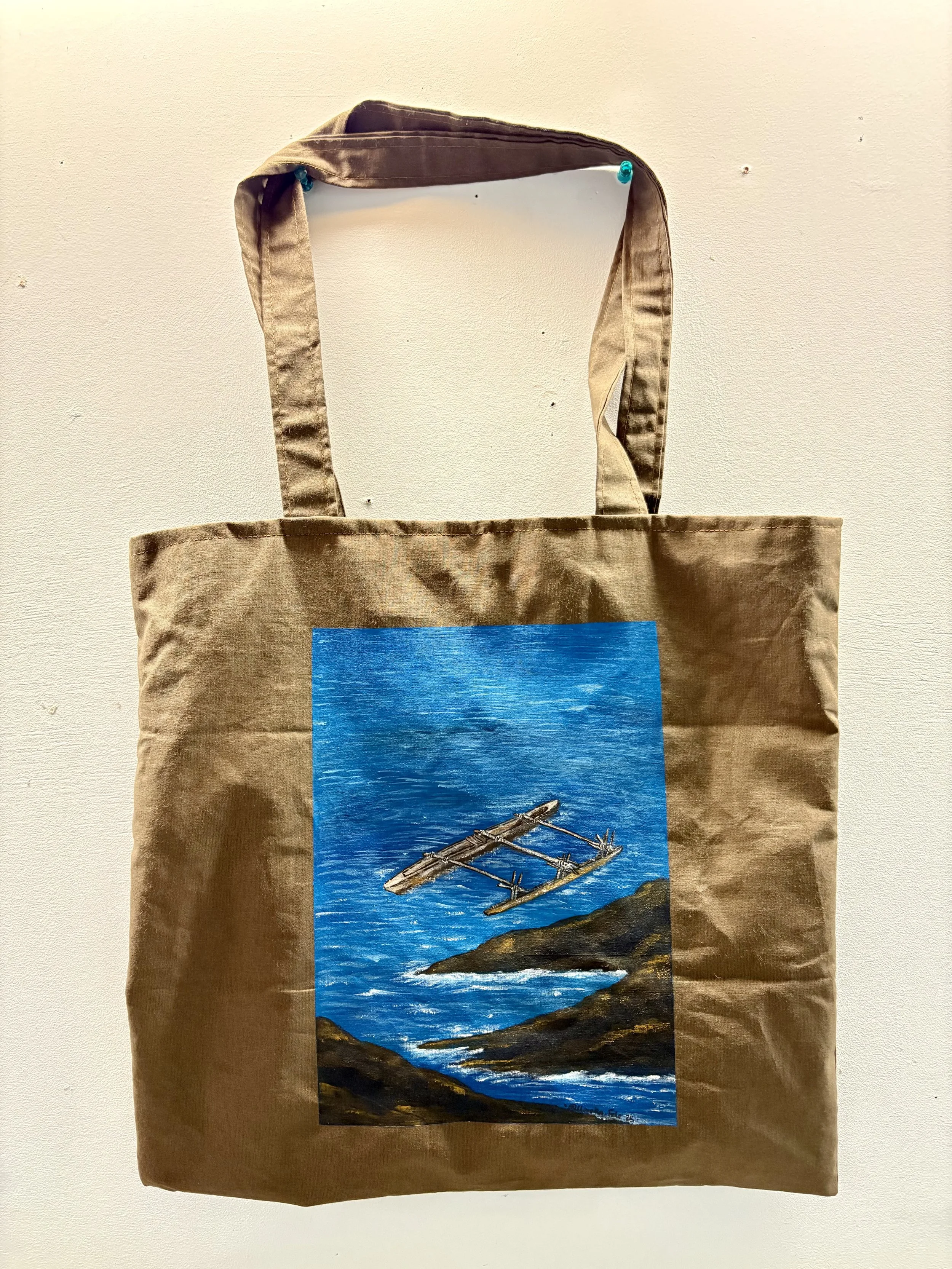 Brown tote bag with a painting of a raft on a blue water body on the front.