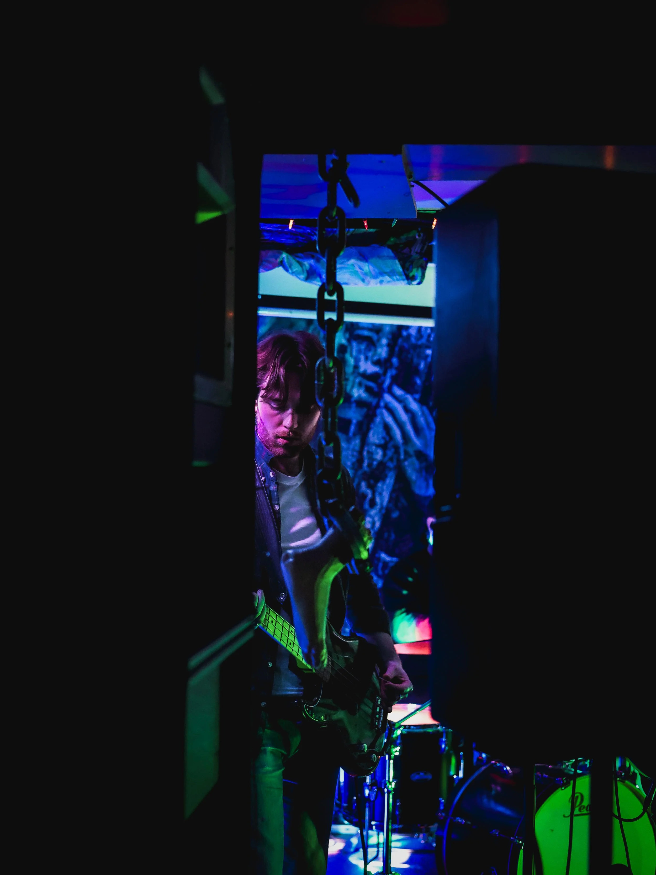 A musician playing an electric guitar in a dark room with colorful LED lights.
