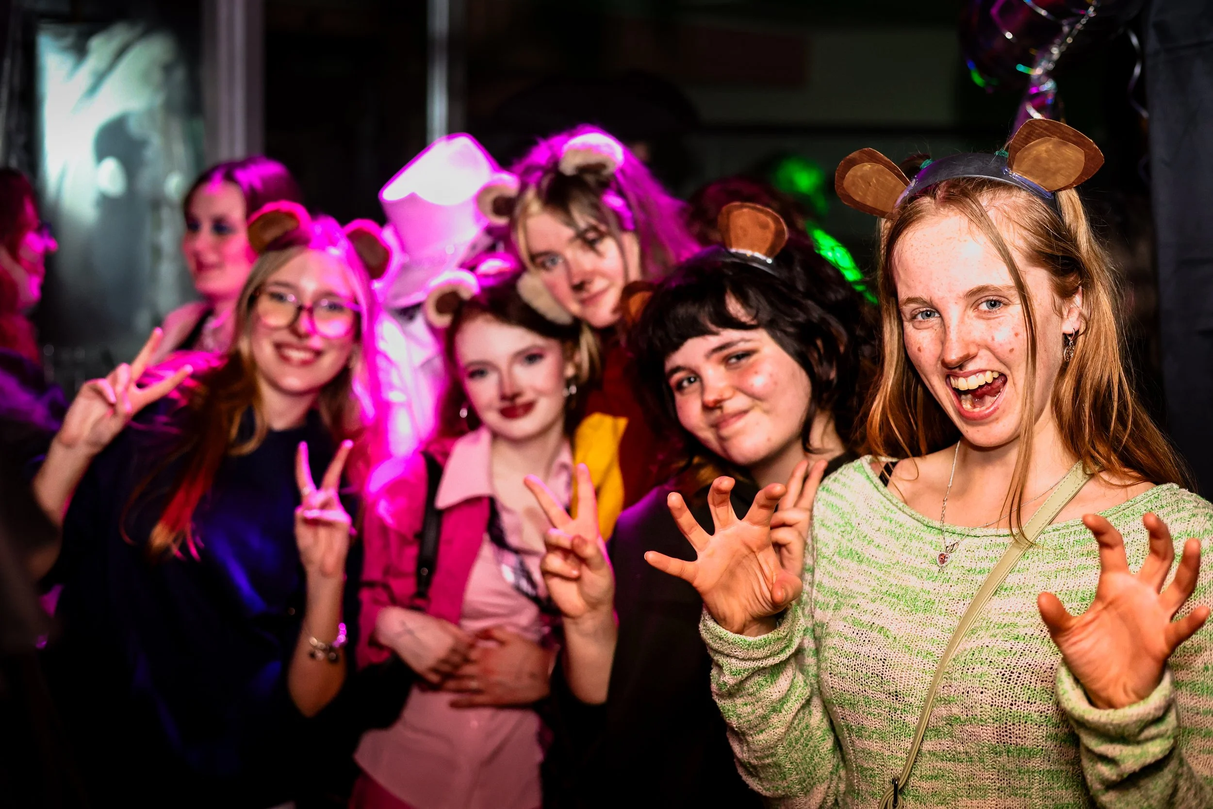Group of young women at a costume party wearing animal ear headbands, smiling and posing for the camera.