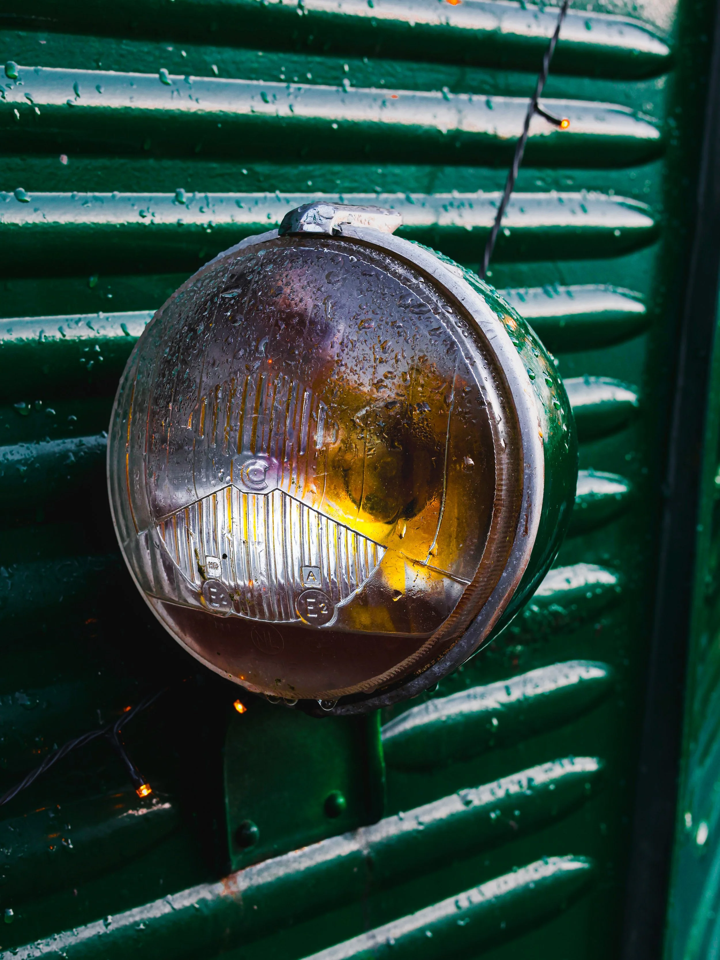Close-up of a wet, foggy turn signal light on a green vehicle, with water droplets visible on the surface.