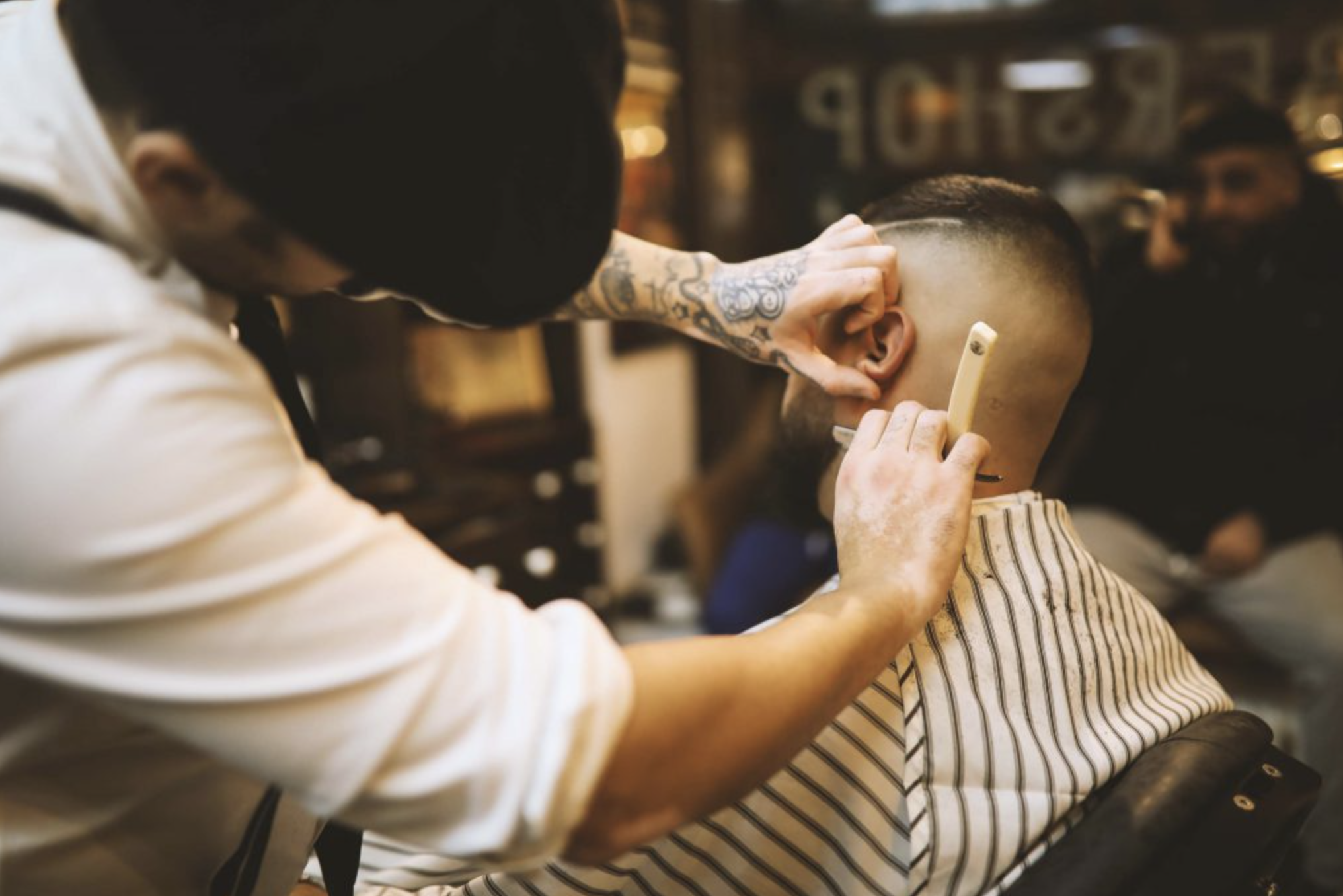 Friseur schneidet einem Kunden mit einem Haarschneidemaschine im Friseursalon.