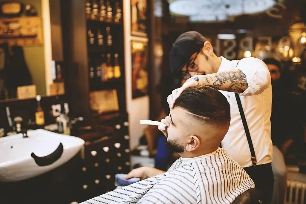Ein Friseur schneidet die Haare eines Mannes im Friseursalon.