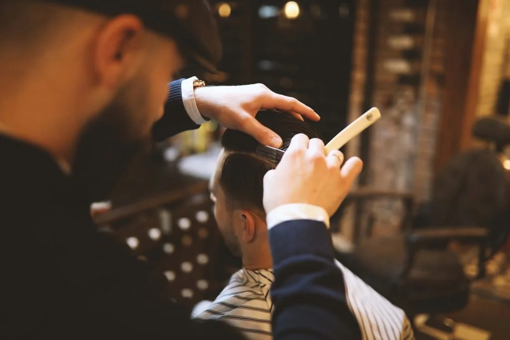 Friseur schneidet einem Kunden die Haare in einem Salon.