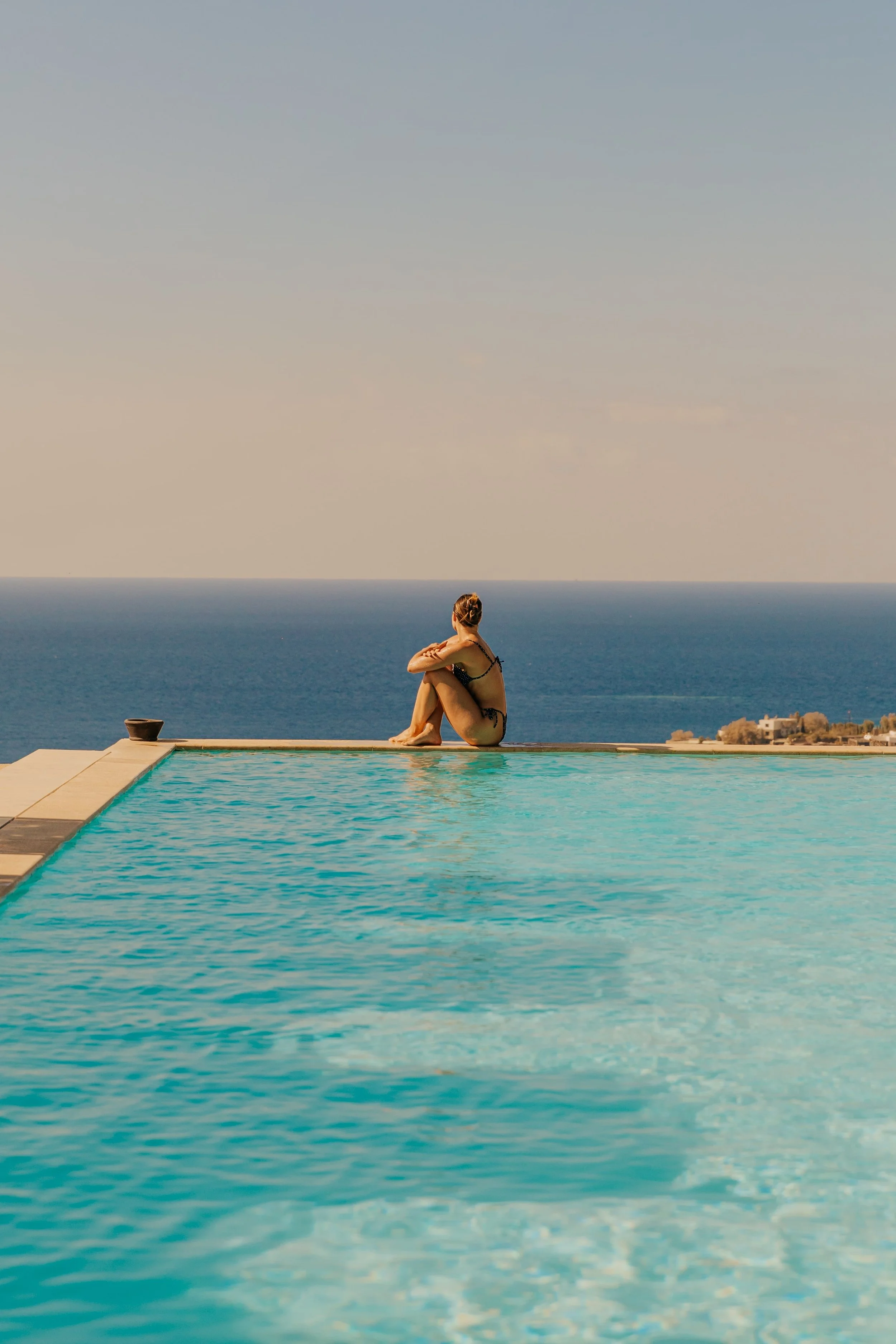 Women sitting poolside, looking out at sea