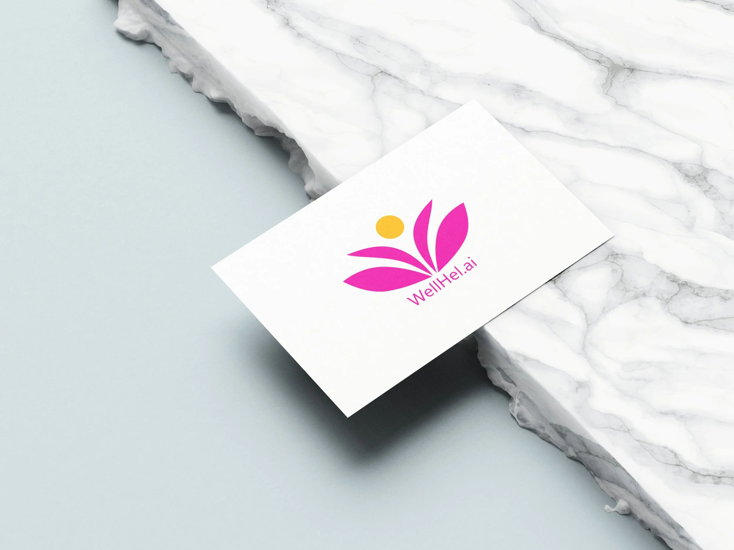 A business card with a pink leaf logo and the text 'WellHel.ai' rests on a black marble surface next to a light blue surface.