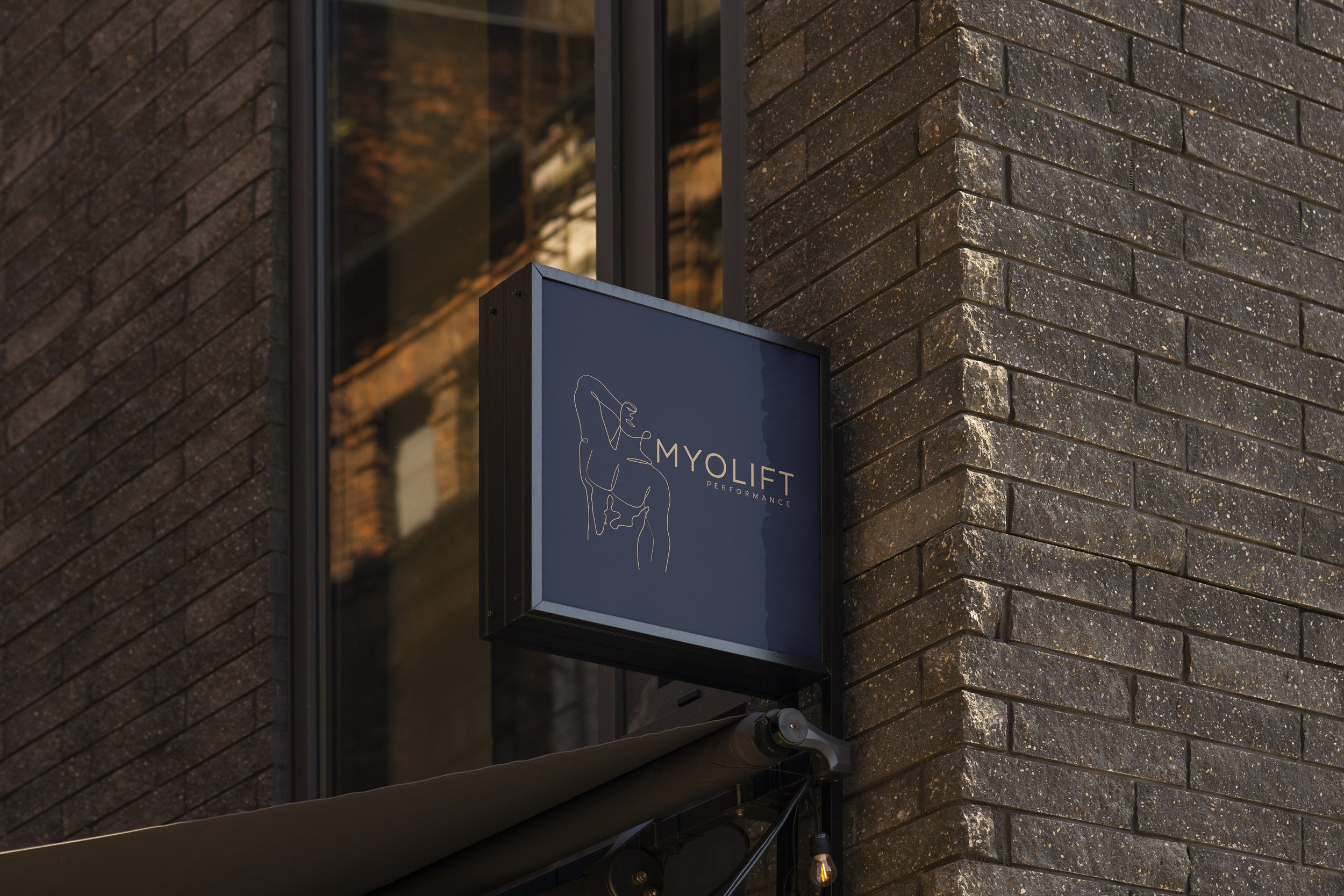 Signboard outside a building with the text 'MYOLIFT PERFORMANCE' and a minimalist line drawing of a person.