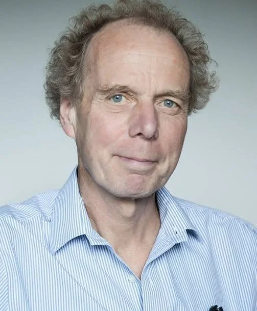 Professor John Rothwell. A middle-aged man with curly hair wearing a light blue striped shirt.
