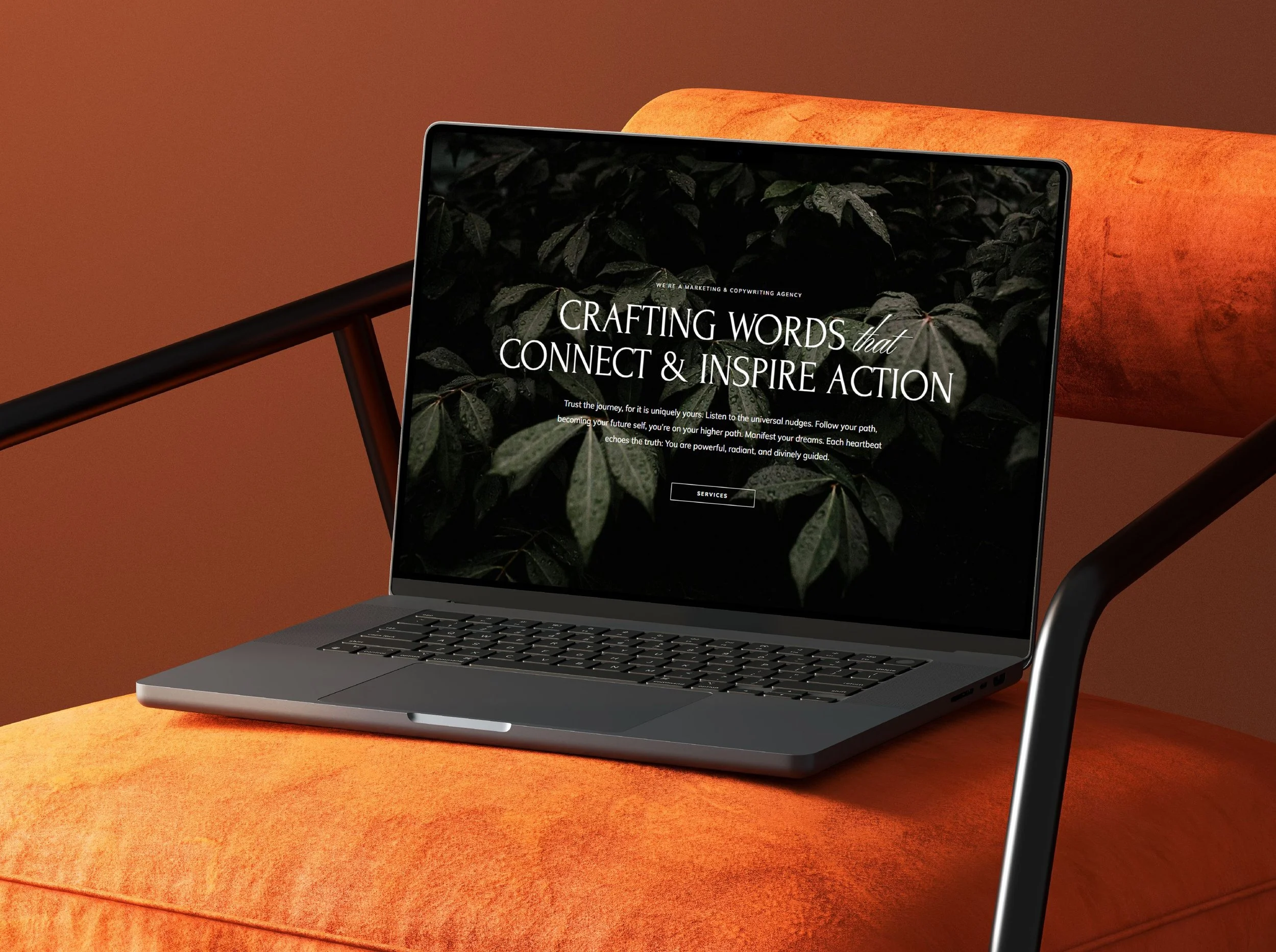 Laptop on an orange velvet chair with a website displayed, featuring dark leafy background and white text.
