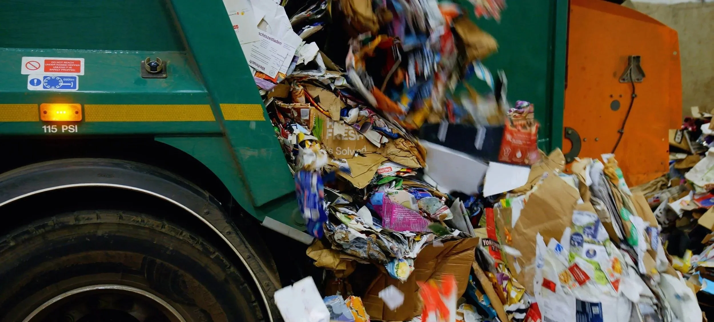 A recycling machine processing crumpled paper waste, with paper debris scattered around.